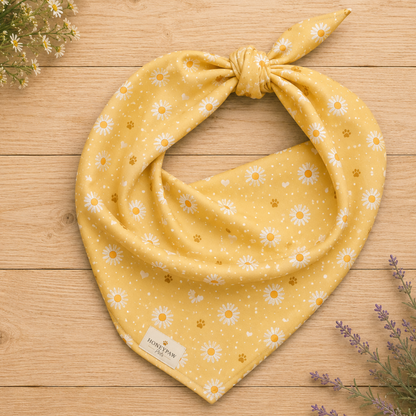 Butter Scout dog bandana featuring white daisy flowers, golden paw prints, and tiny hearts on a buttery yellow background by HoneyPaw Pets.