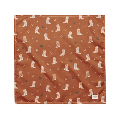 Cowboy Rover western dog bandana featuring western cowboy boots, horseshoes, and paw prints on a burnt orange background by HoneyPaw Pets.