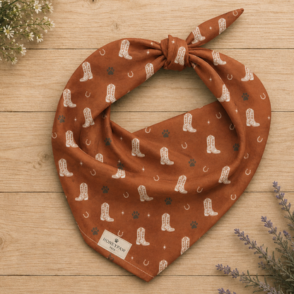 Cowboy Rover western dog bandana featuring western cowboy boots, horseshoes, and paw prints on a burnt orange background by HoneyPaw Pets.