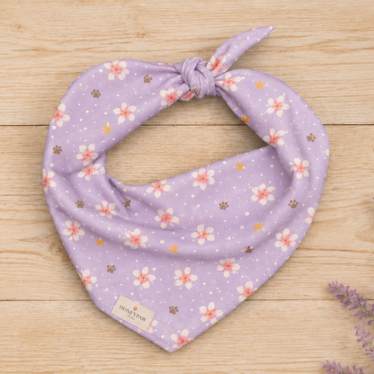 Island Scent dog bandana featuring pink plumeria flowers, paw prints, and golden stars on a lavender background by HoneyPaw Pets.