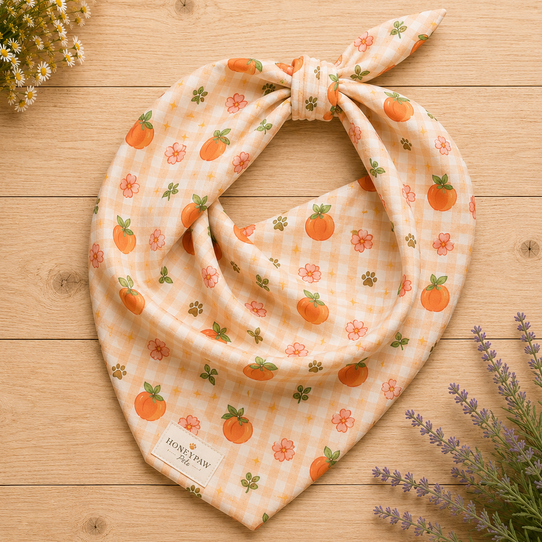 Peachy Pup dog bandana featuring ripe peaches, floral accents, and a soft peach plaid pattern on a cream background by HoneyPaw Pets.