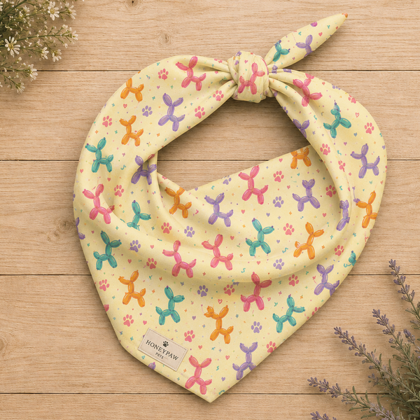 Sunny Squeaks birthday dog bandana featuring colorful balloon animals, confetti and paw prints on a light yellow background by HoneyPaw Pets